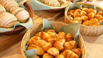 Une variété de pains et de viennoiseries présentés dans des paniers en osier sur une table.