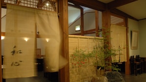 En traditionell japansk inredning med tatamimattor på golvet, en shojiskärm och en liten stenträdgård.