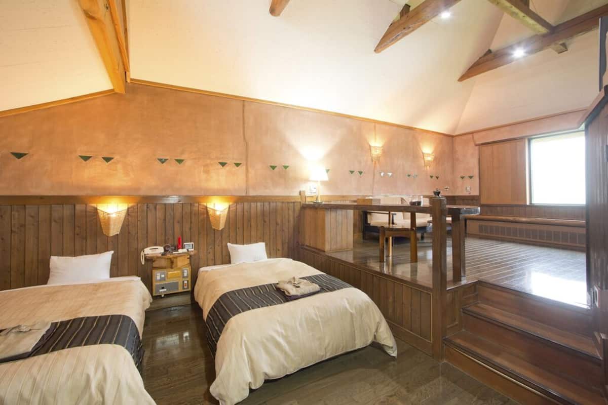 Una habitación con paredes de madera, una cama, una mesita de noche, una lámpara y una ventana.