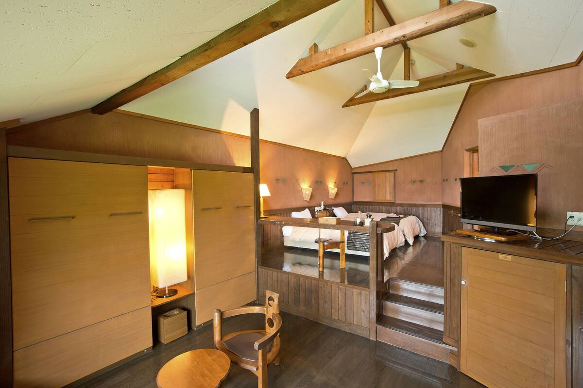A cozy room with a bed, a TV, and a wooden chair.