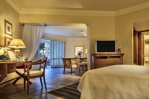 A hotel room with a bed, a desk with a lamp, a chair, a television, and a view of the outdoors through a window.