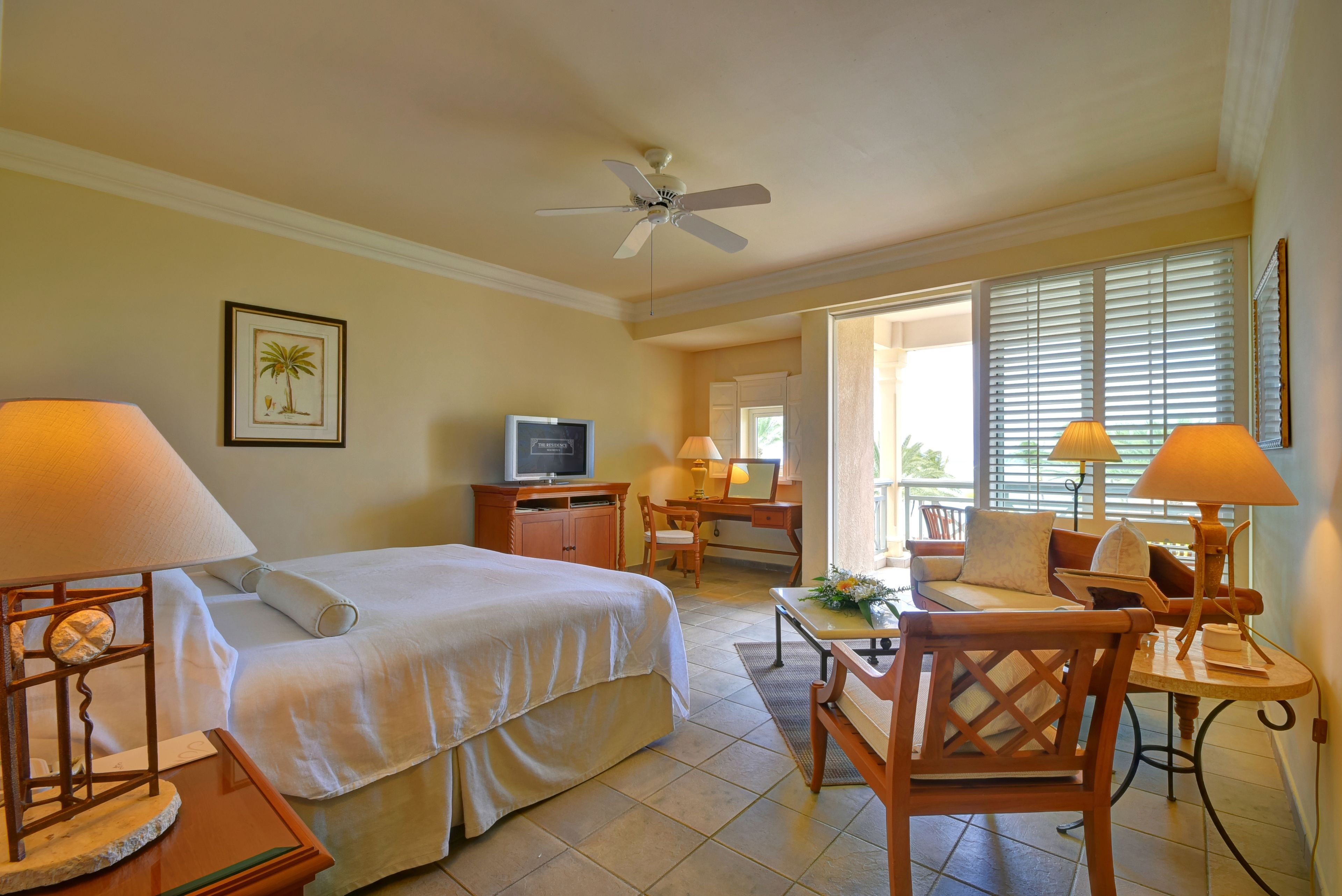 Quarto de hotel com cama, escrivaninha, cadeira e televisão.
