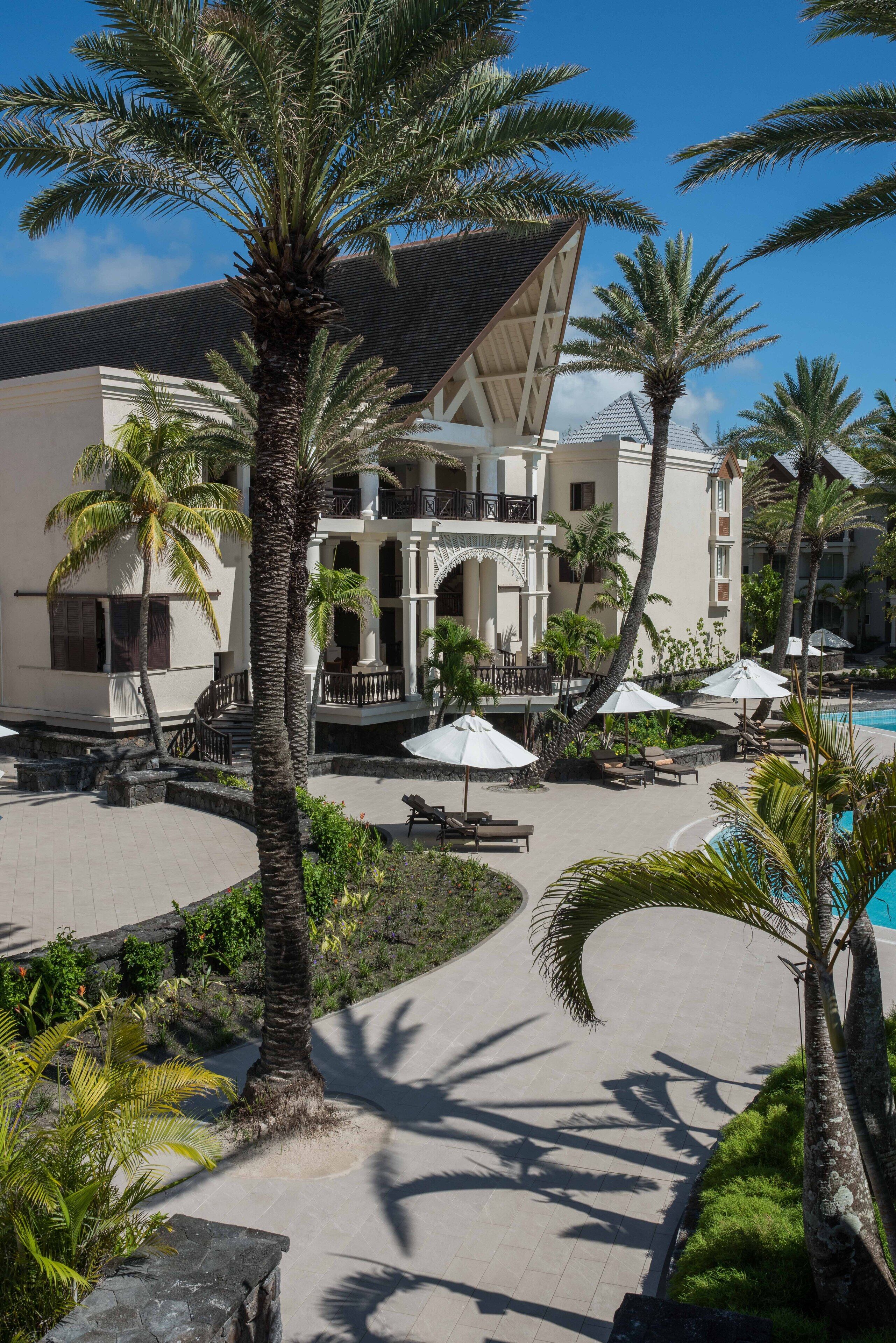 Un resort con piscina, palmeras y un edificio con balcón.