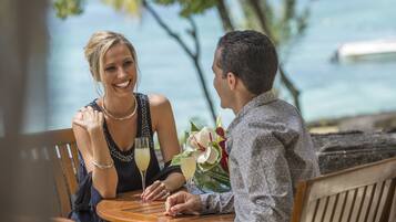Un couple est assis à une table en plein air, avec vue sur l’océan.