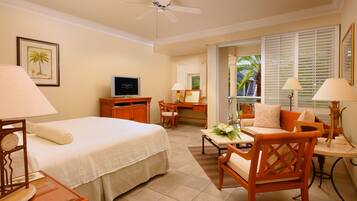 A hotel room with a bed, desk, chair, and a small table with a flower arrangement.