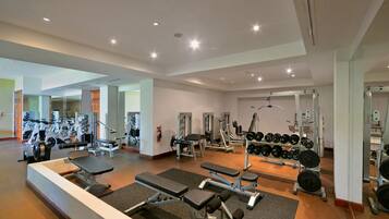 Une salle de sport moderne équipée de divers appareils d’exercice, de miroirs et de supports pour les poids.