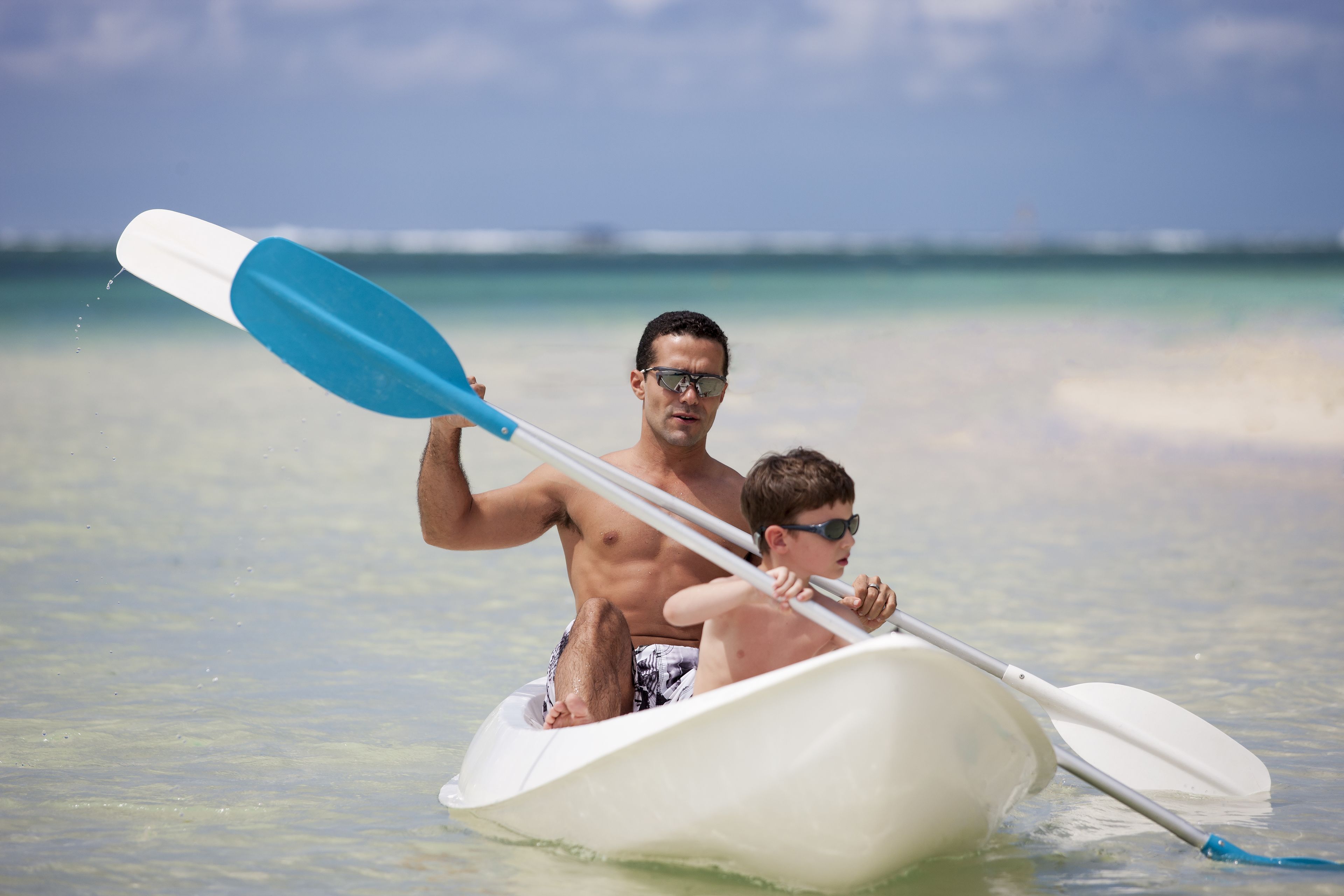 Un hombre y un niño en un barco pequeño sobre un mar tranquilo.