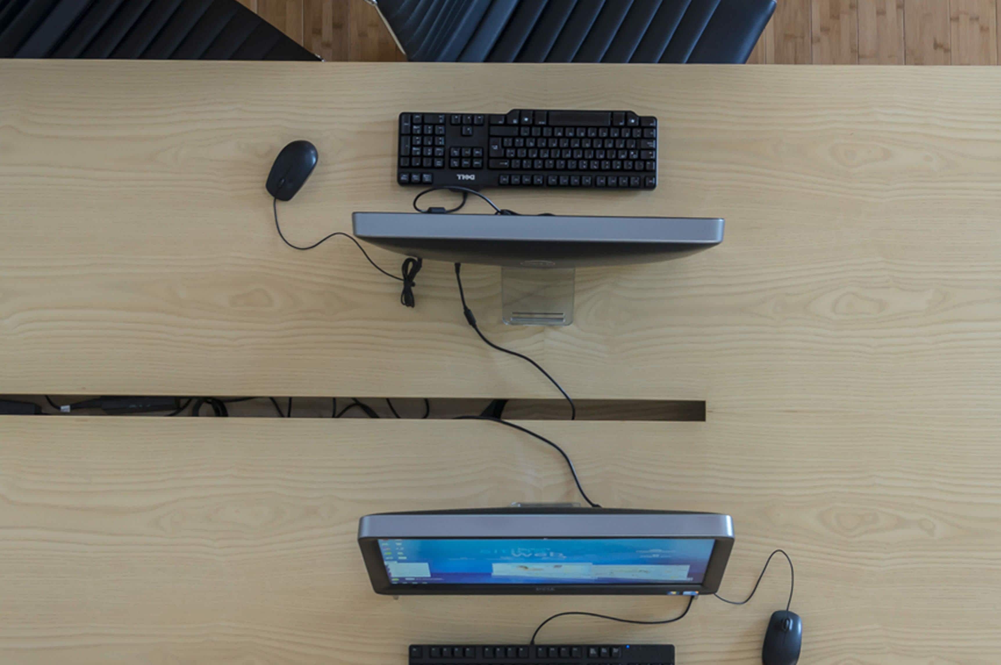 A wooden desk with a keyboard, mouse, and monitor.