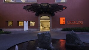 A building with a large entrance, a sign reading "Fiesta Inn Hotels Business Class," and a water feature with rocks in the foreground. - Fiesta Inn Queretaro (Querétaro)