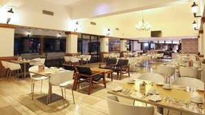 A spacious restaurant with multiple dining areas, including a bar and a seating area with tables and chairs. - Fiesta Inn Queretaro (Querétaro)
