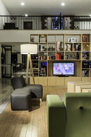 Un salon moderne avec un téléviseur, des sièges et une bibliothèque.