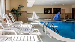 Une piscine intérieure dotée de chaises longues blanches, d’un mur carrelé et d’un espace abrité.
