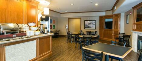 A hotel dining area with a buffet, multiple tables, and chairs.
