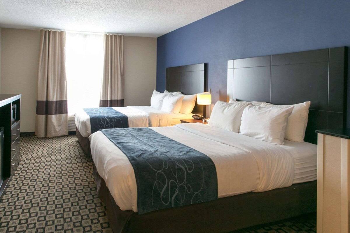 Une chambre d’hôtel avec deux lits, un bureau et une lampe.