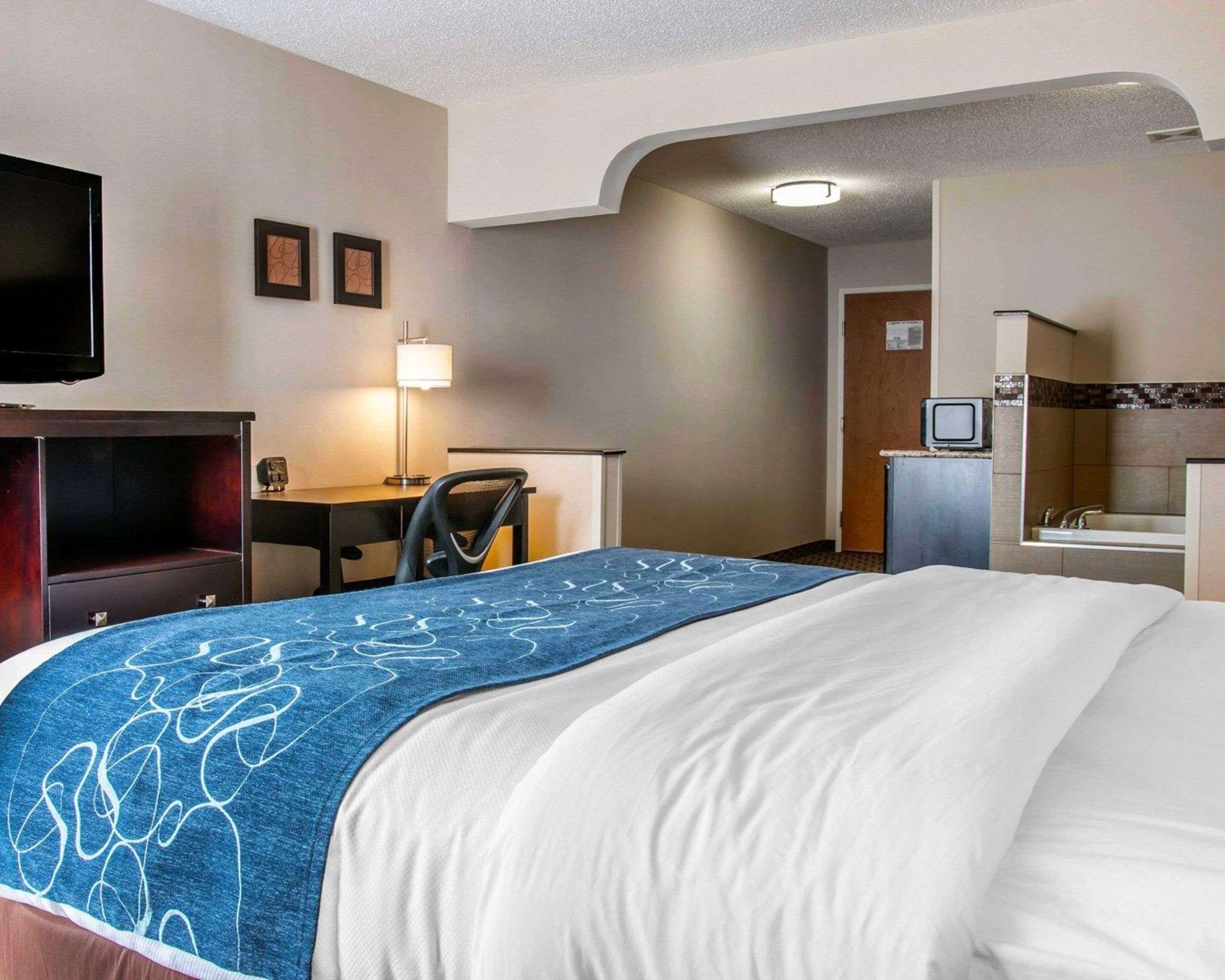 A hotel room with a bed, a desk, a chair, a television, and a bathroom.