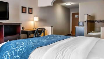 A hotel room with a bed, a desk, a chair, a television, and a bathroom.