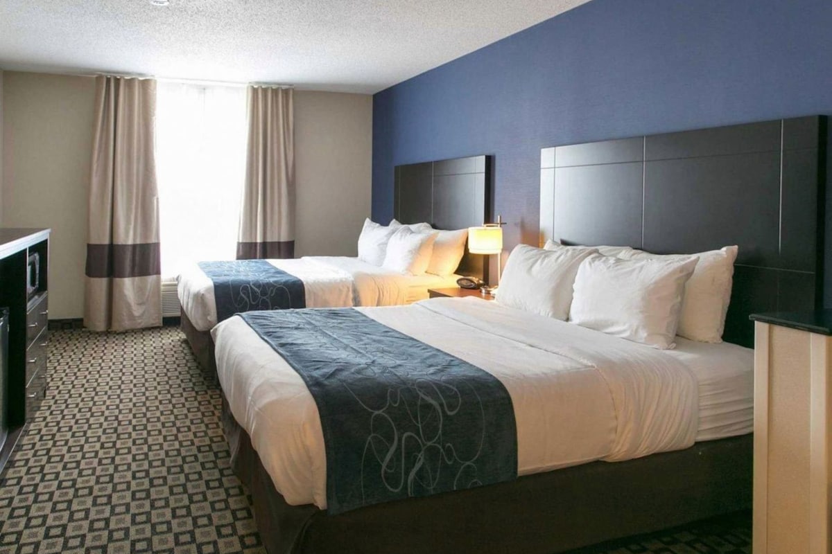 Une chambre d’hôtel avec deux lits, un bureau et une lampe.