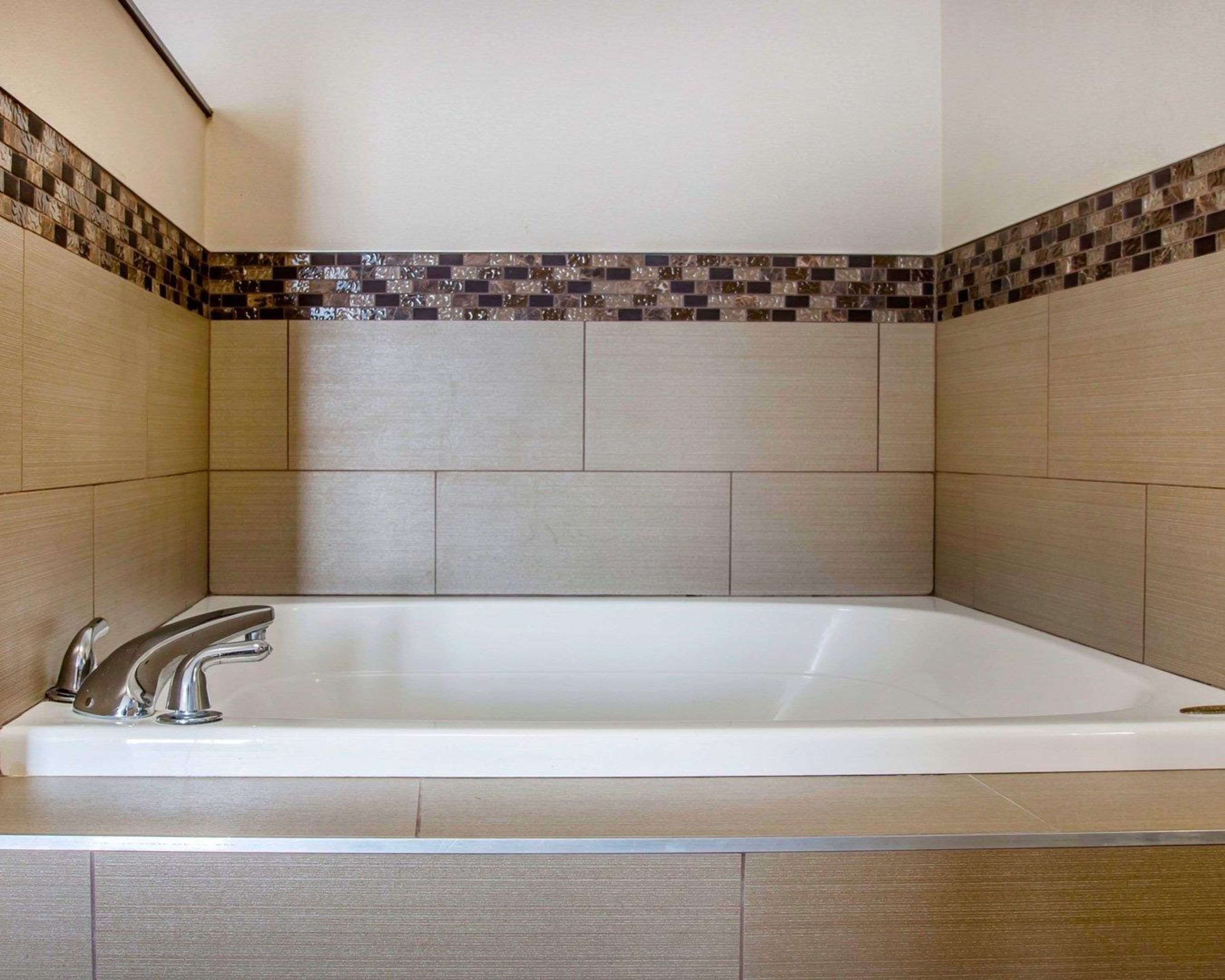 A modern bathroom with a freestanding bathtub, tiled walls, and a wooden vanity.