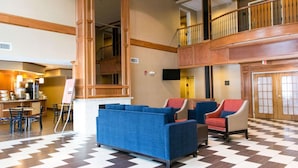 Un hall d’hôtel avec un sol à carreaux, un espace salon et un escalier menant à un étage supérieur.