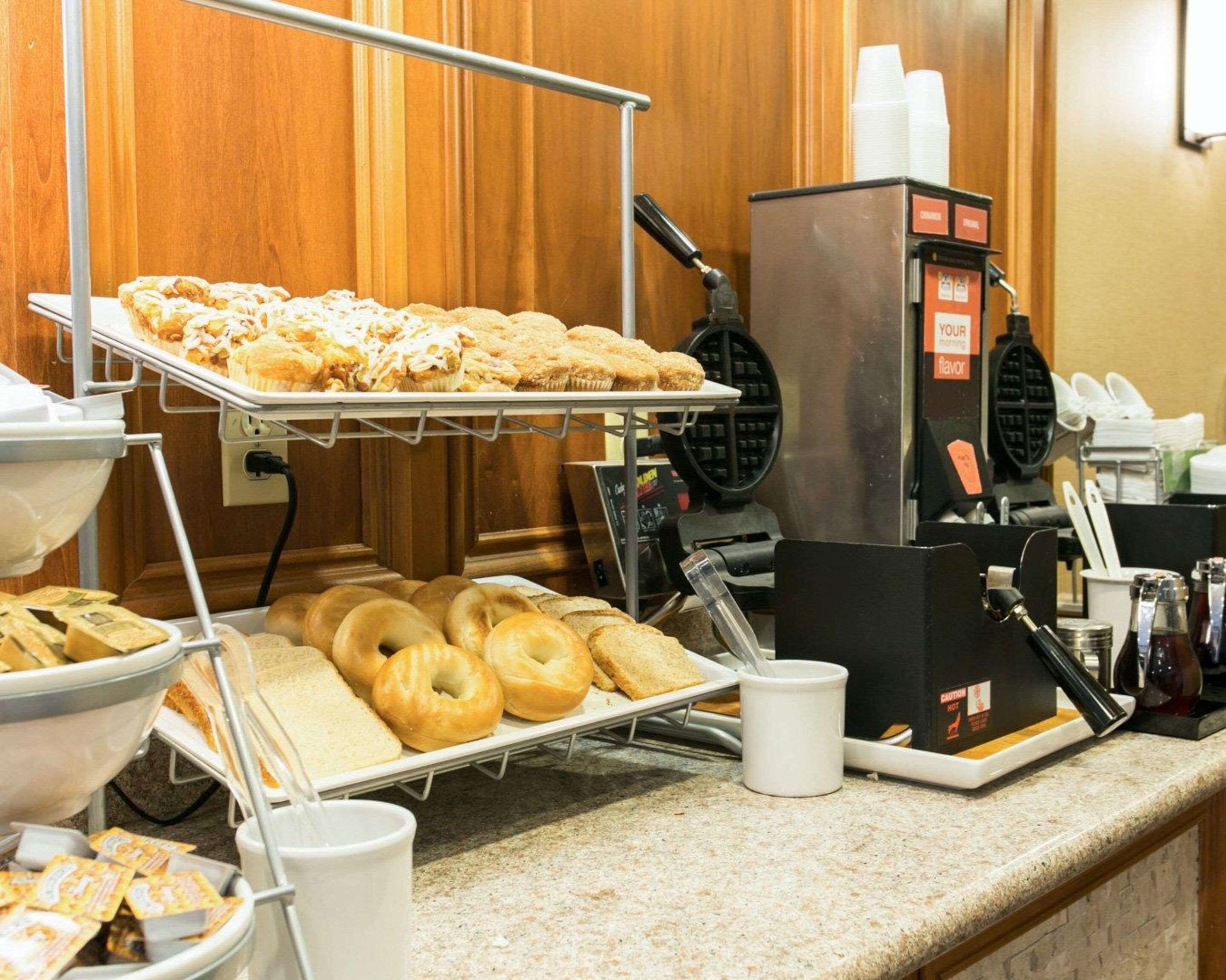 A breakfast buffet with pastries, bagels, and a waffle maker.