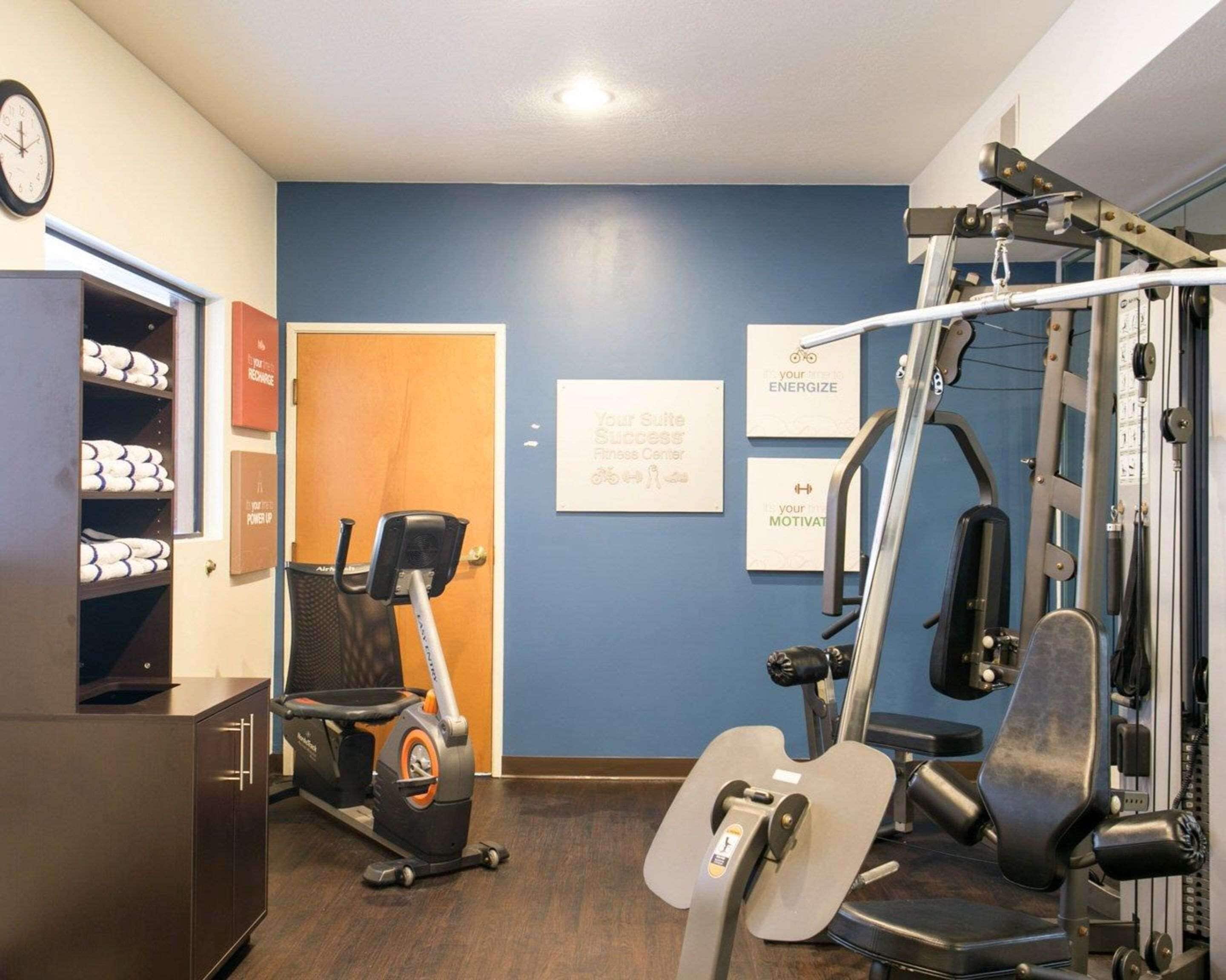 A fitness center with exercise equipment, a wall clock, and motivational posters.