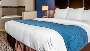Une chambre d’hôtel avec un grand lit, une salle de bain avec une baignoire et une table de chevet avec une lampe.