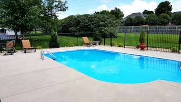 Relax by the rectangular pool surrounded by a deck and lush greenery.