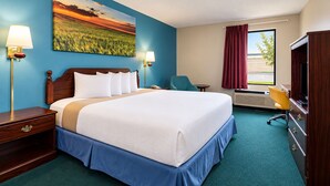 A hotel room with a large bed, two bedside tables, a desk with a chair, a television, and a painting of a sunset over a field. - Days Inn by Wyndham Battlefield Rd/Hwy 65 (Springfield)