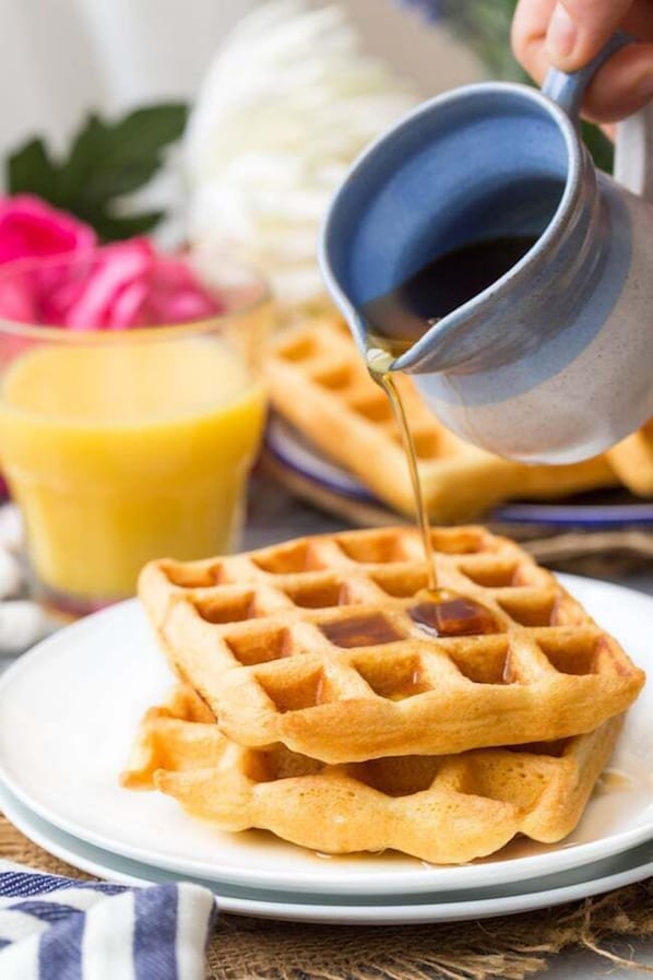 A plate of waffles with syrup being poured over them. - Days Inn by Wyndham Battlefield Rd/Hwy 65 (Springfield)