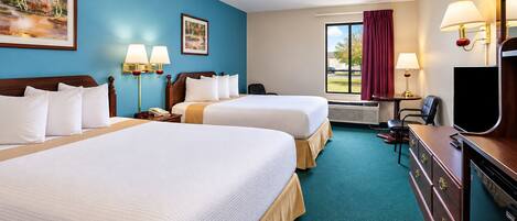 A hotel room with two beds, a desk, a television, and a window with curtains.