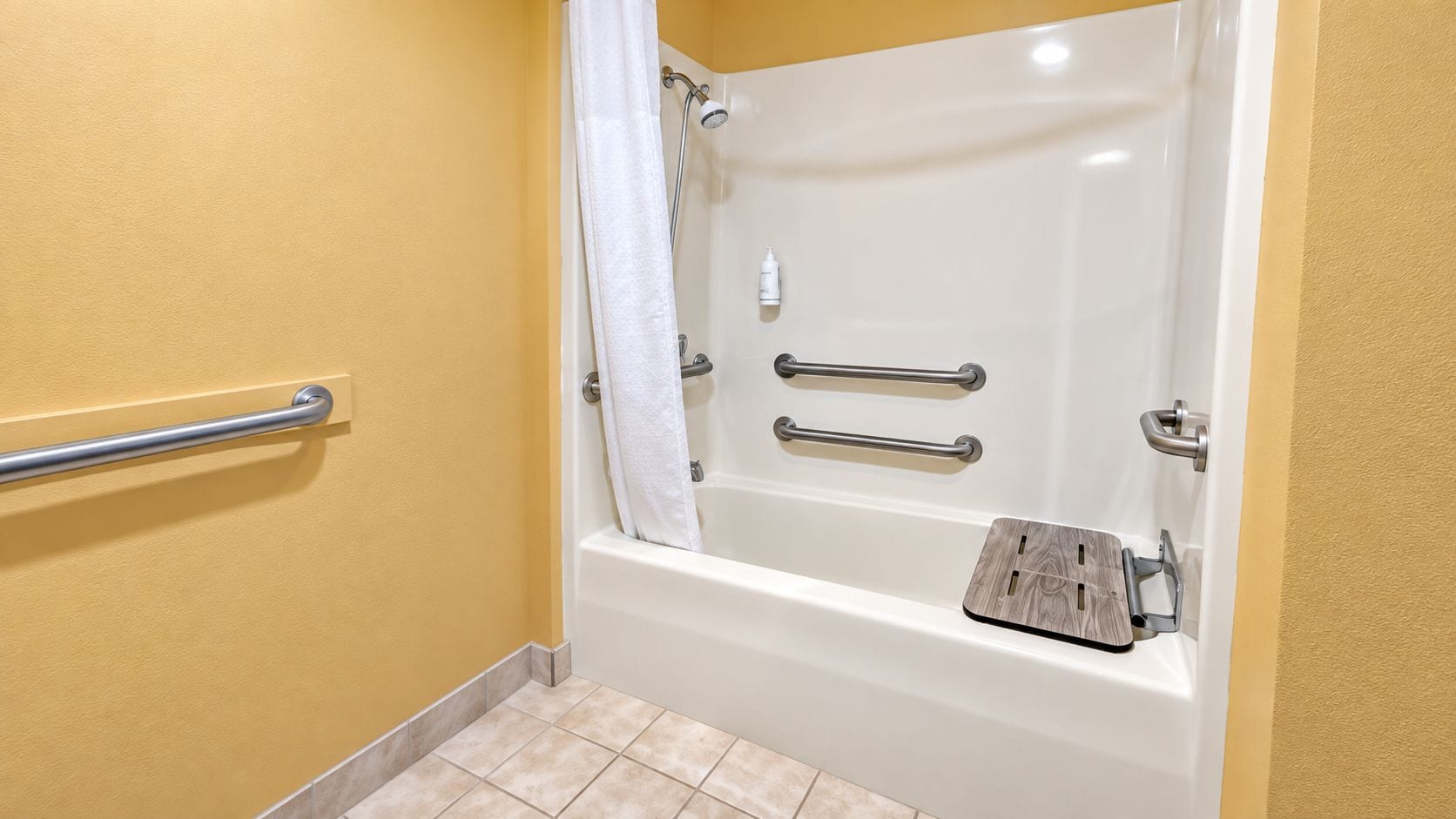 A bathroom with a bathtub, grab bars, and a shower curtain.