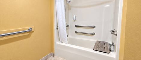 A bathroom with a bathtub, grab bars, and a shower curtain.