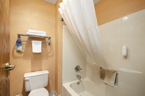 A bathroom with a toilet, a shower with a curtain, and a towel rack with towels. - Days Inn by Wyndham Battlefield Rd/Hwy 65 (Springfield)