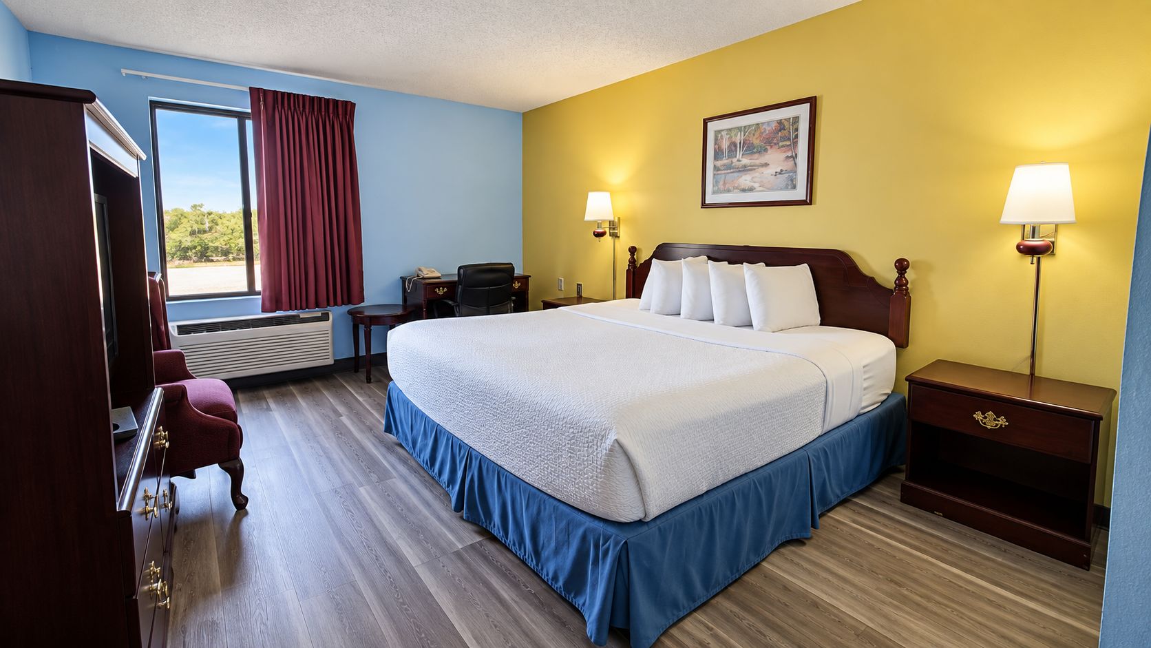 A hotel room with a bed, bedside tables, a desk, a chair, a lamp, and a painting on the wall.