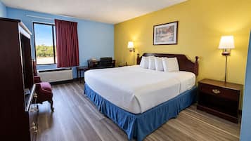 A hotel room with a bed, bedside tables, a desk, a chair, a lamp, and a painting on the wall.