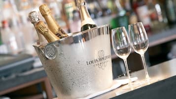 Un ambiente de bar con un cubo de champán Louis Roederer y dos copas sobre la barra.