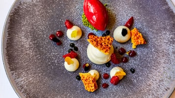 Un plato de postre con diversas frutas y una baya roja sobre una superficie texturizada.