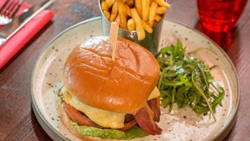 A plate with a burger, fries, and a glass of red beverage.