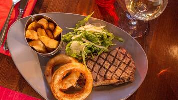 A plate with grilled steak, onion rings, and a side salad.