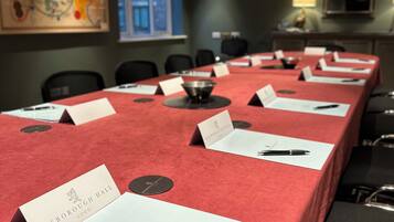 Un salón de conferencias con una larga mesa cubierta de tarjetas de identificación rojas y bolígrafos.