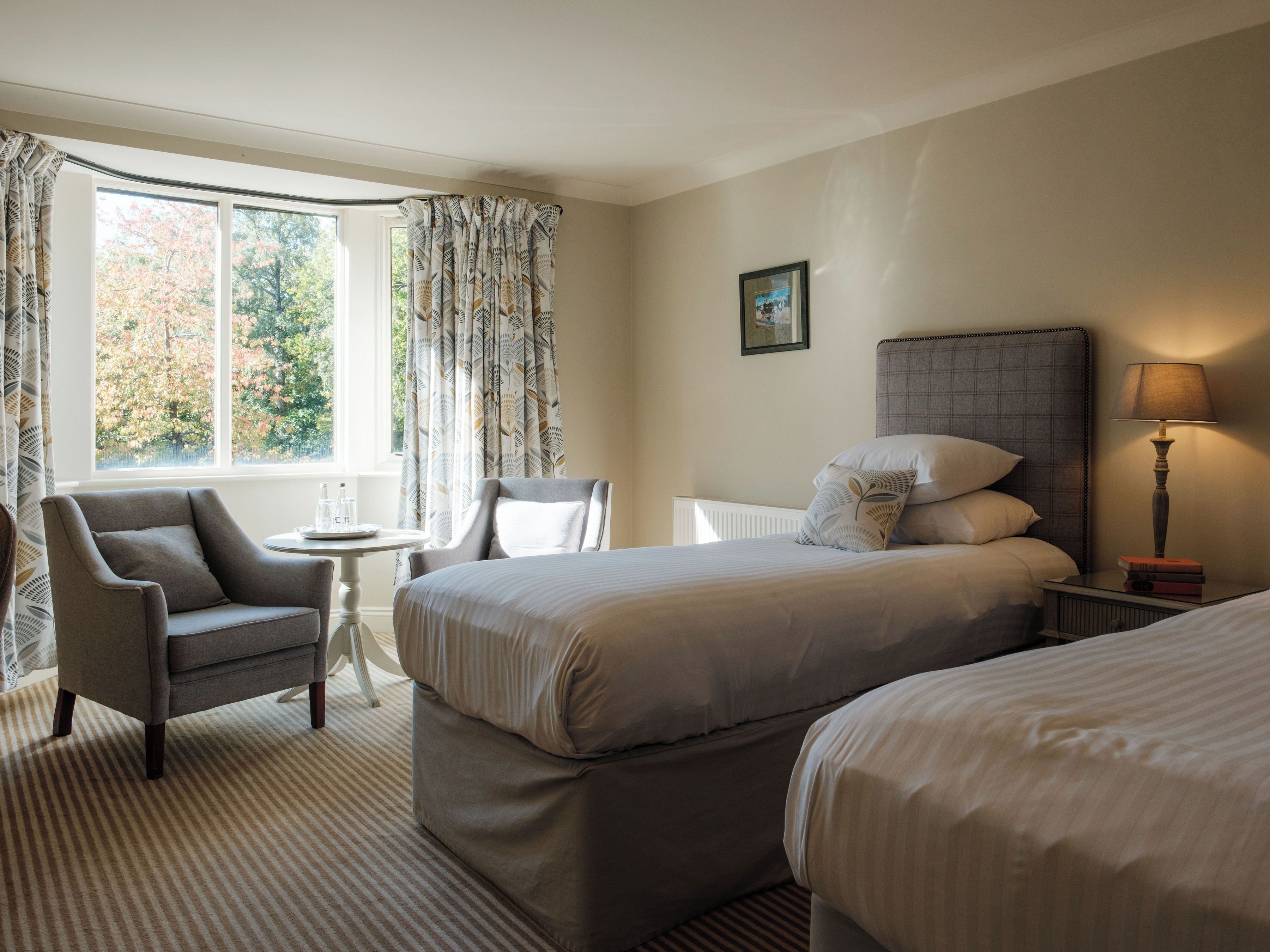 Une chambre d’hôtel avec deux lits, une chaise, une petite table et une lampe.