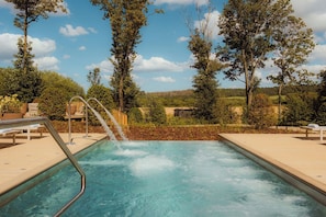 A pool with a waterfall feature surrounded by trees and a clear sky. - Gisborough Hall Country House Hotel & Spa (Guisborough)