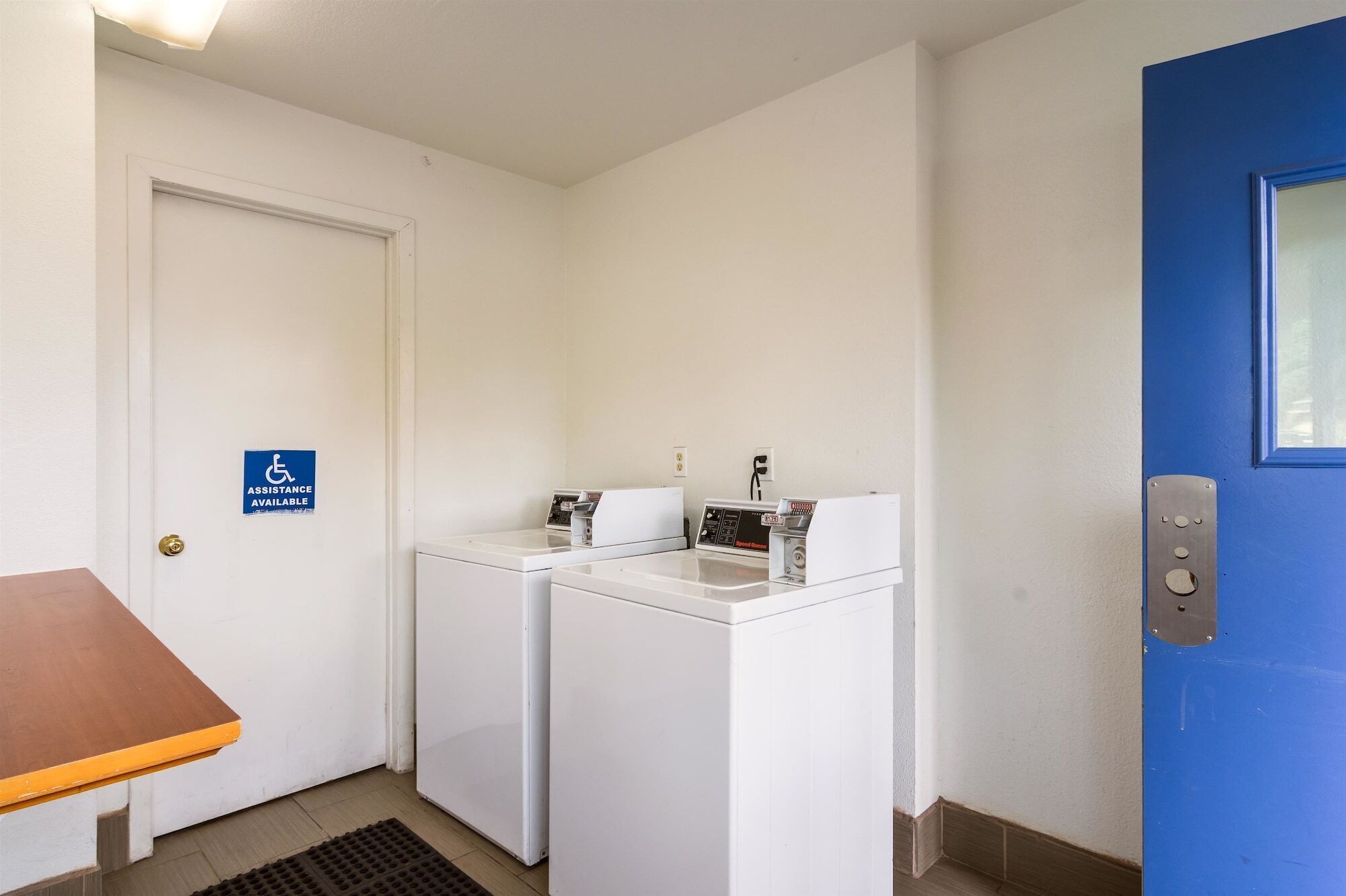 A laundry room with two washing machines, a blue door, and a handicap-accessible sign.