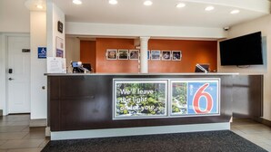 A hotel reception desk with a sign reading "We'll leave the light on for you." - Motel 6 Vancouver, WA (Vancouver)