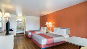 Une chambre d’hôtel avec deux lits, un bureau, une télévision et une salle de bain visible à travers une porte ouverte.