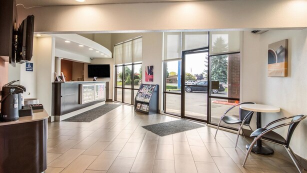 A reception area with a counter, a TV, a wheelchair accessibility sign, a display board, and a view of the parking lot. - Motel 6 Vancouver, WA (Vancouver)