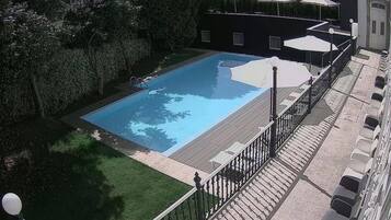 Una piscina al aire libre de temporada, sombrillas, tumbonas