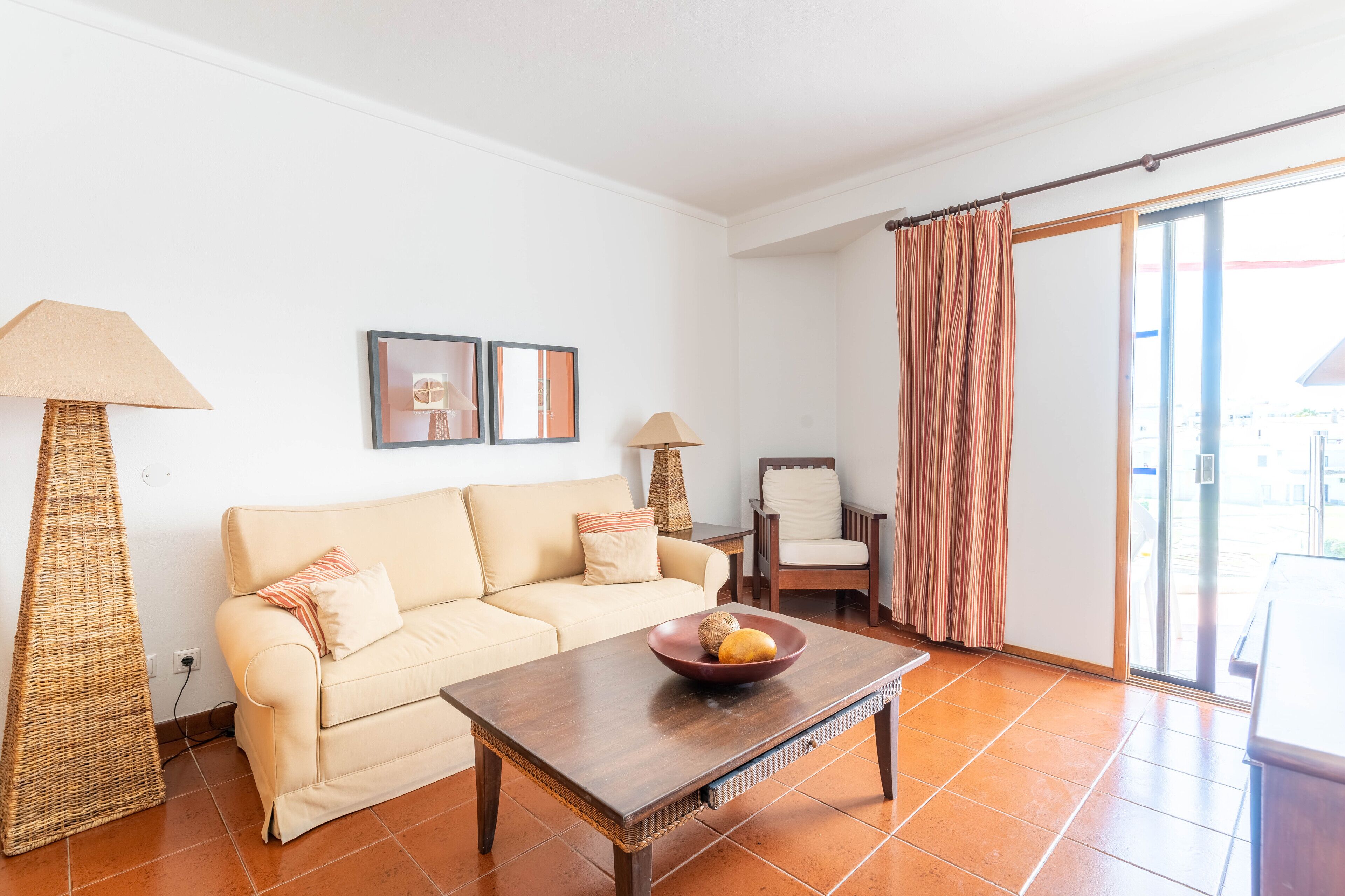A living room with a sofa, a coffee table with fruit, a lamp, and a chair.