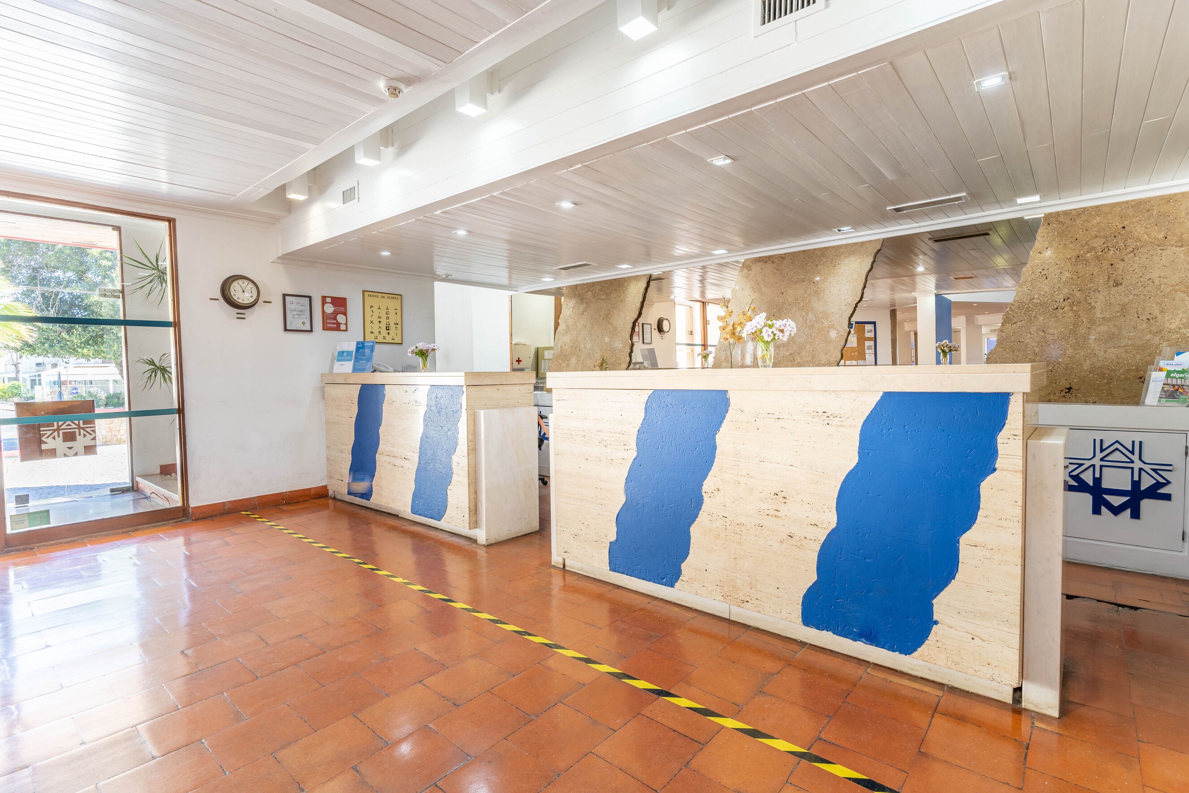 A reception area with a wooden ceiling, tiled floor, and a glass door leading outside.