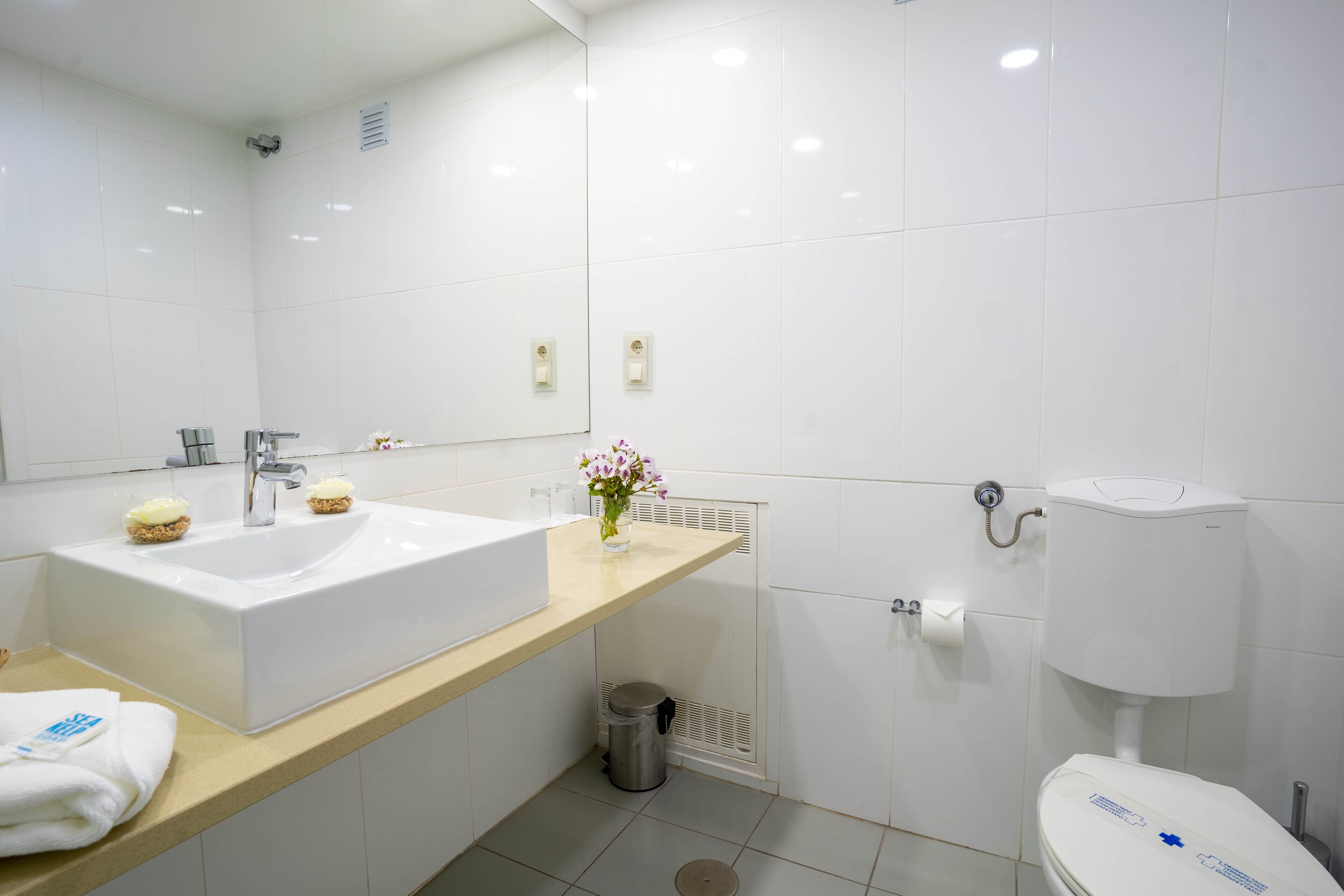 Un bagno moderno con un lavandino spazioso, un water e uno specchio.